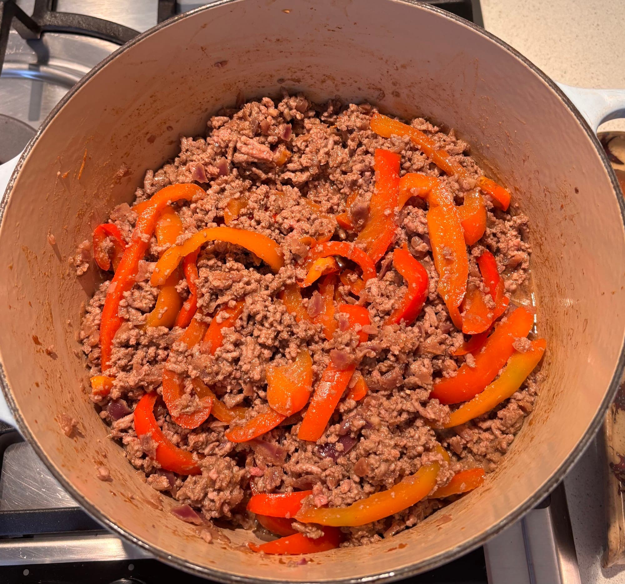 Minced beef browning with red and orange pepper strips in a pot, chilli con carne recipe, Cooking It Bristol