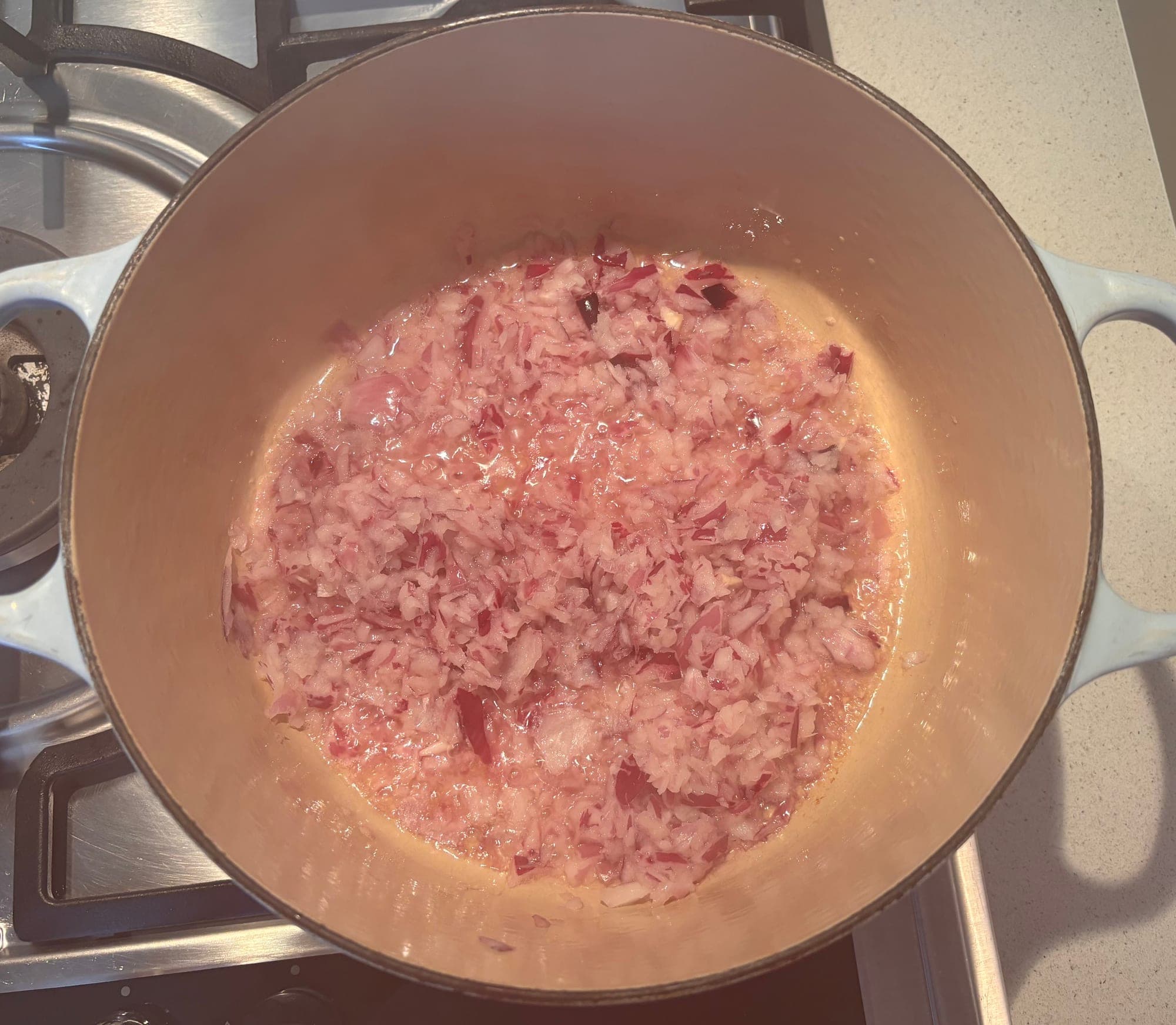 Chopped red onion and garlic softening in a cast iron pot for chilli con carne, Cooking It Bristol